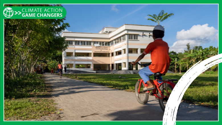 Boy cycling torwards a cyclone shelter that doubles as a primary school in Bangladesh.