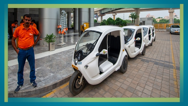 Picture of a man standing next to electric rickshaw vehicles in India