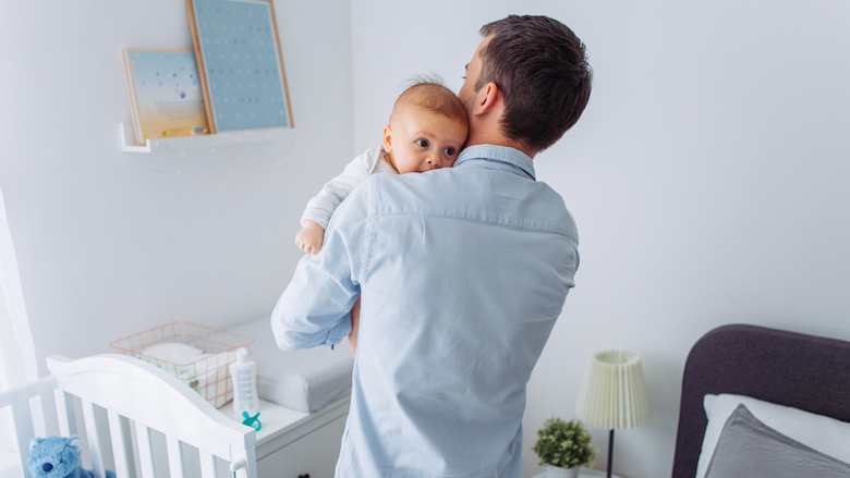 A father is holding a baby in a room