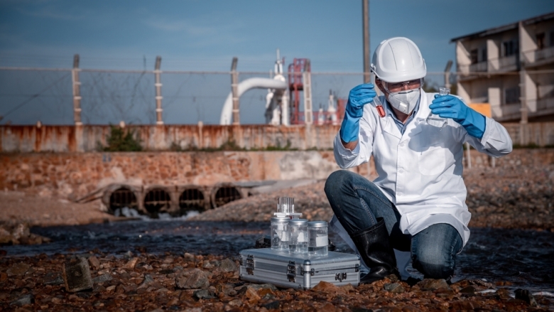 Scientist wearing protective uniform and gloves performs water analysis 
