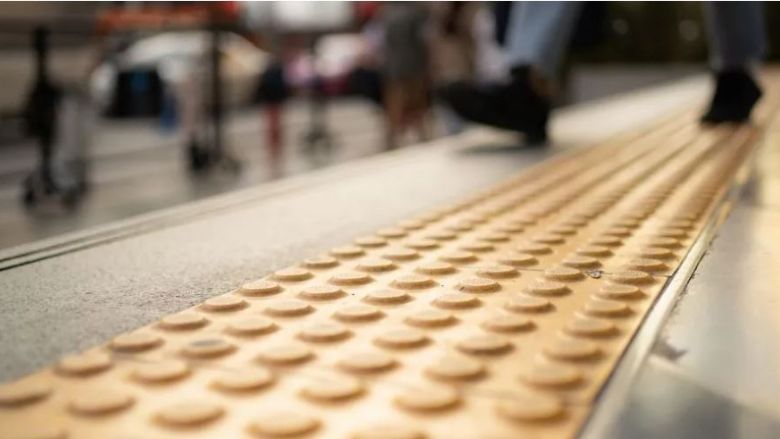 A pedestrian walking on a on textured walkway, designed to adhere to universal design