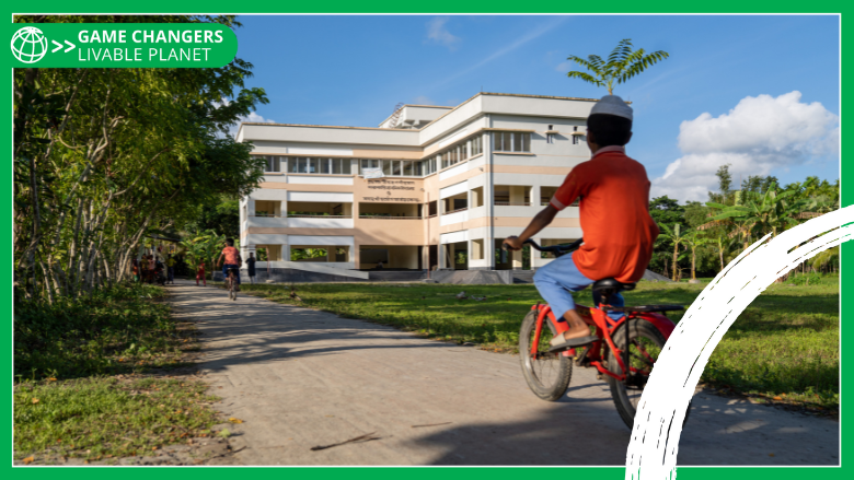 Boy cycling torwards a cyclone shelter that doubles as a primary school in Bangladesh. - with Game Changers branding