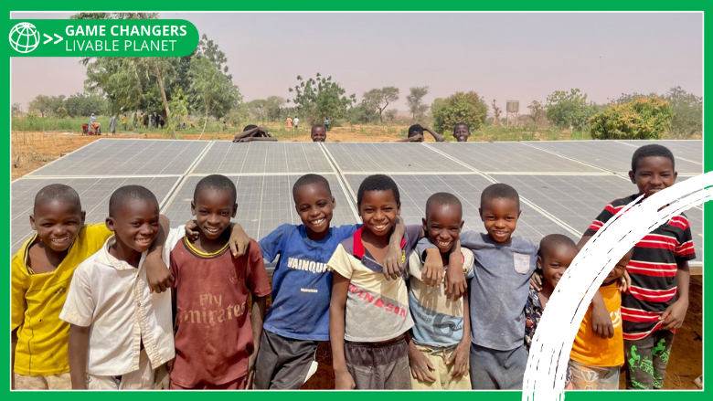 Group of smiley children in front of solar panels in Niger. - with Game Changers branding