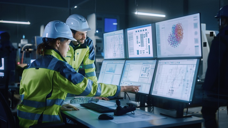Engineers looking a production line data on computer screens