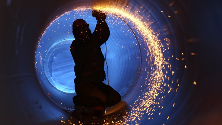 Welder inside pipe on construction site