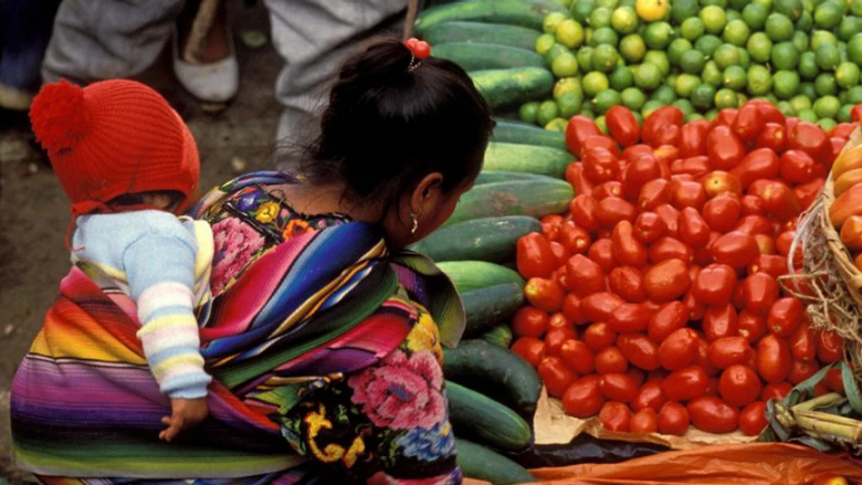 Women with child on back looking at vegetables