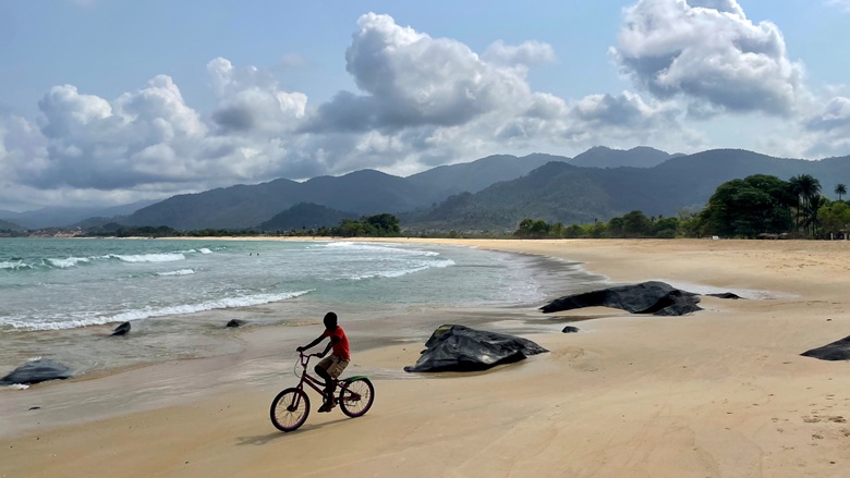 Boy riding bicycle on Bureh Beach in Sierra Leone