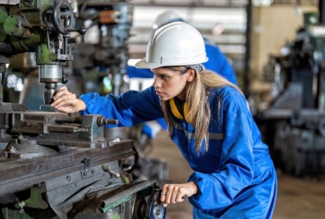 A woman works at a sewing machine in a factory.
